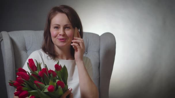 Femme avec un bouquet de tulipes parlant au téléphone — Video