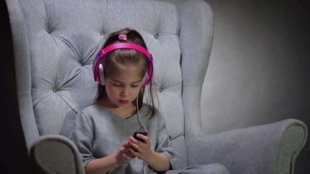 Bájos lány zenét hallgat a széken — Stock videók