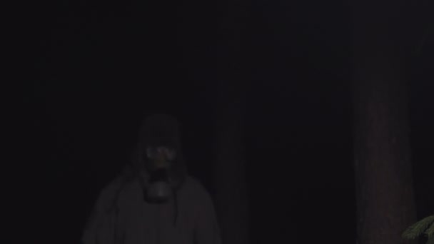 Людина в газовій масці втікає від коронавірусу в лісі вночі — стокове відео