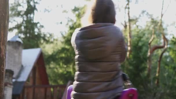 Niña girando en un columpio en el bosque de primavera — Vídeos de Stock