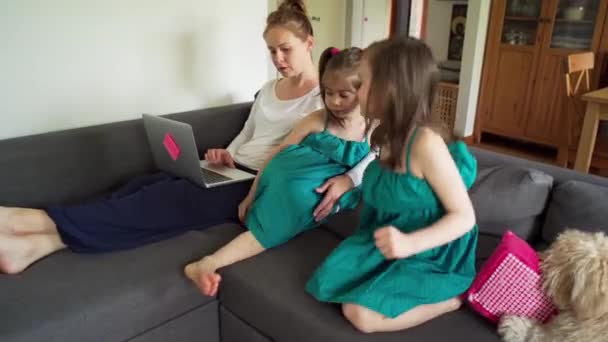 Hermanas ver la televisión y la madre trabaja de forma remota en un ordenador durante una pandemia — Vídeos de Stock