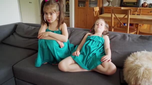 Маленькие девочки смотрят телевизор дома на диване во время пандемии — стоковое видео
