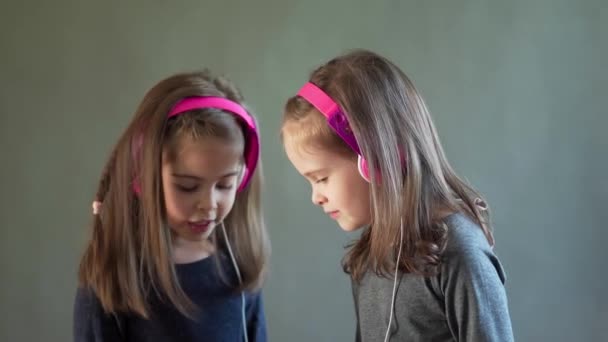 Twee schattige meisjes met koptelefoon luisteren naar muziek en dans — Stockvideo