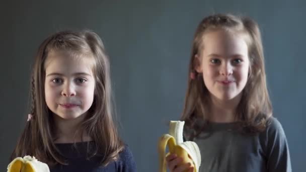 Dos chicas adorables están comiendo un plátano delicioso — Vídeo de stock