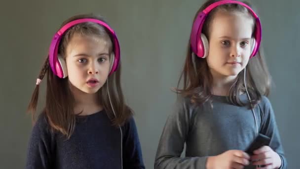 Duas meninas adoráveis com fones de ouvido ouvir música e dança — Vídeo de Stock