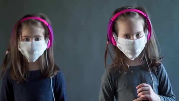 Dos chicas adorables en una máscara con auriculares escuchar música — Vídeo de stock