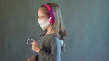 Kulaklıklı, maskeli hoş bir kız müzik dinliyor.