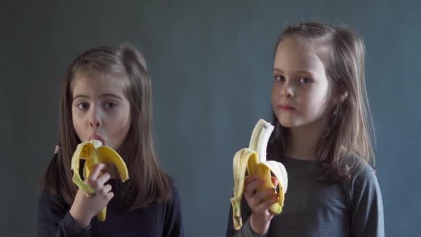 Twee schattige meisjes zijn eten een heerlijke banaan — Stockvideo