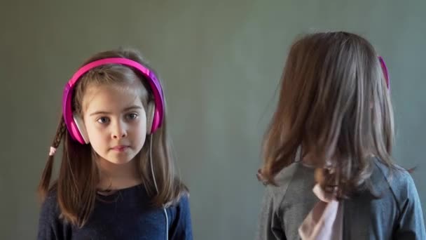 Két imádnivaló lány fejhallgatóval zenét és táncot hallgat. — Stock videók