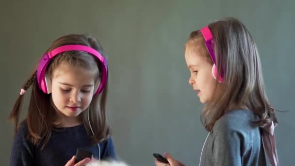 Duas meninas adoráveis com fones de ouvido ouvir música e dança — Vídeo de Stock