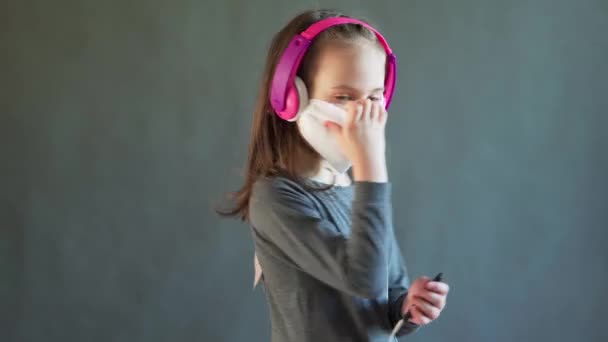 Menina encantadora em uma máscara com fones de ouvido ouve música — Vídeo de Stock