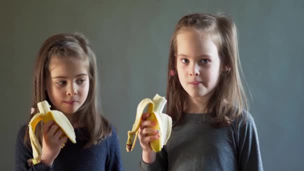 Two adorable girls are eating a delicious banana — Stock Video