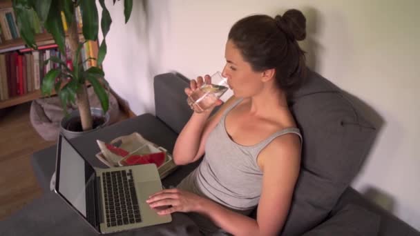 Женщина работает из дома и пьет воду во время пандемии в замедленной съемке — стоковое видео