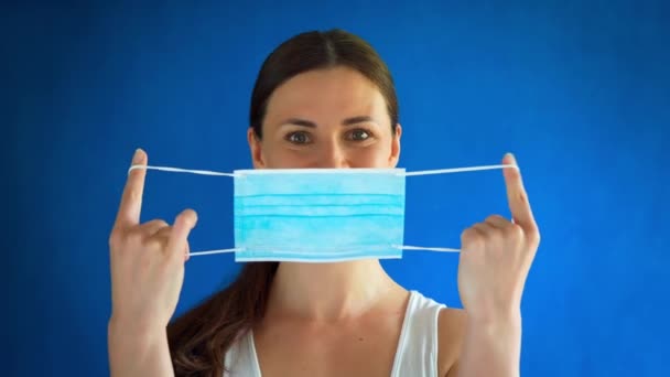 Mujer con camisa blanca muestra cómo usar una máscara durante una pandemia — Vídeo de stock