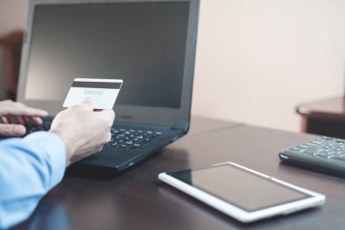 Kredi kartı tutan ve dizüstü bilgisayar kullanarak bir adam. Online ödeme ve sho