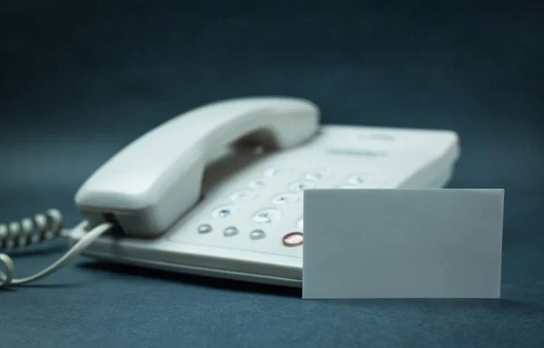 Büro-Telefon mit leerer Visitenkarte auf blauem Hintergrund. — Stockfoto