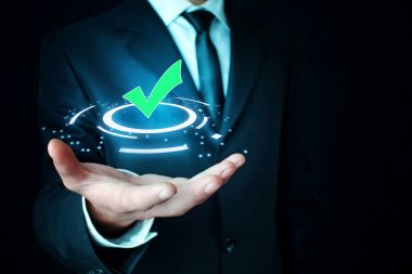 Yeşil onay işareti simgesi tutan adam.