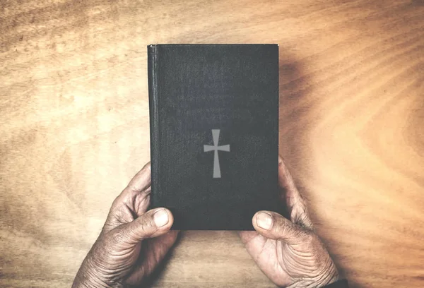 Régi kezek a Biblia, a fa háttér. — Stock Fotó