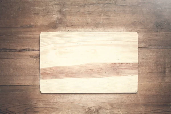 Tabla de cortar de madera vacía sobre un fondo de madera . — Foto de Stock