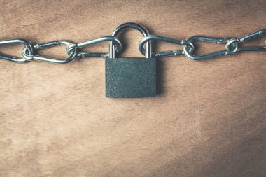 Asma kilit ve zincirleri ahşap arka plan üzerinde.