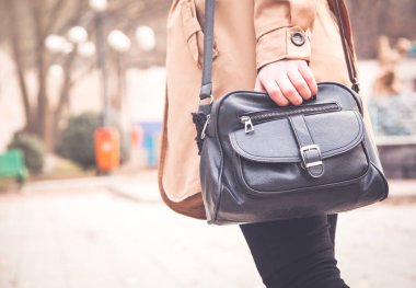 Kadın parkta bir siyah deri çanta.