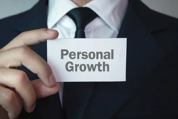Businessman showing Personal Growth text on business card.
