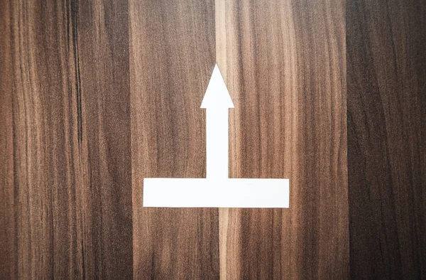 Paper arrow on a wood background.
