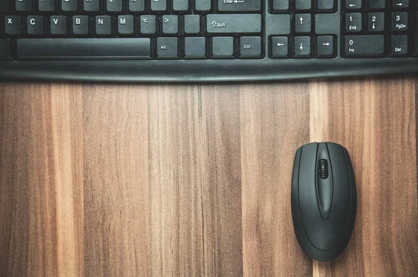 Computer keyboard with mouse on the wood background.