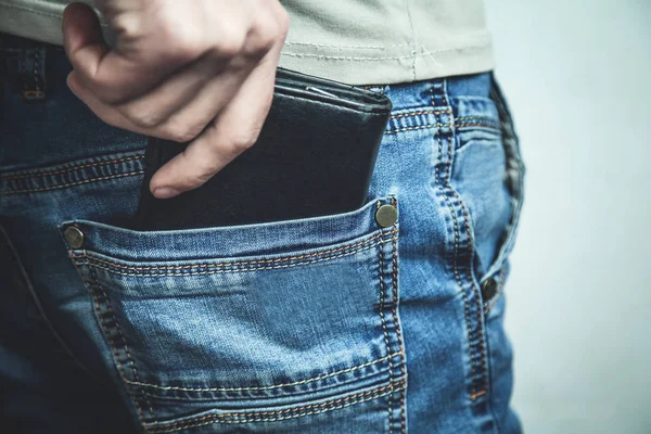 Man pulls black wallet from his pocket of jeans.