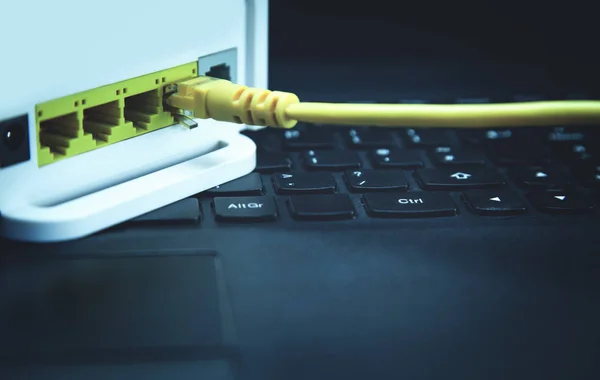 Κίτρινο καλώδιο συνδεδεμένο σε ένα router για το φορητό υπολογιστή. — Φωτογραφία Αρχείου