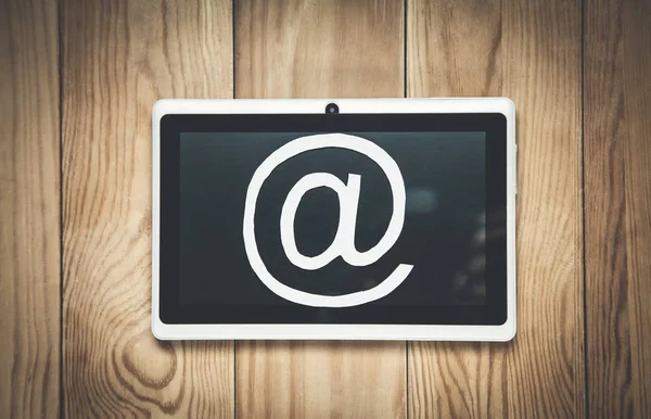 Símbolo de correo electrónico de papel con tableta sobre fondo de madera . —  Fotos de Stock