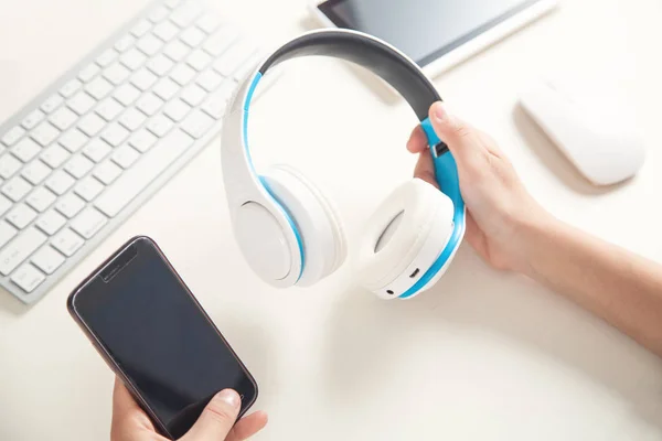 Hands holding headphones with smartphone. Listening music — Stock Photo, Image
