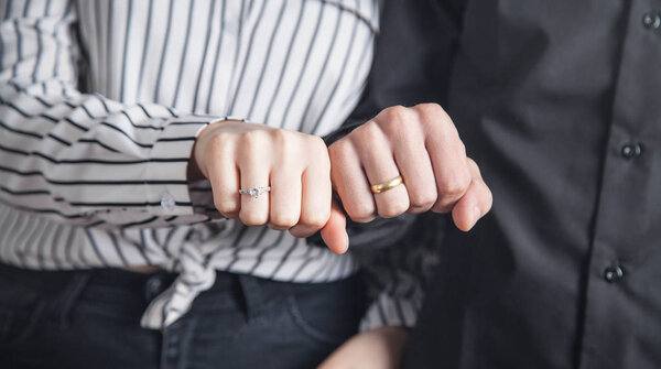 Hands of a guy and a girl with wedding ring.