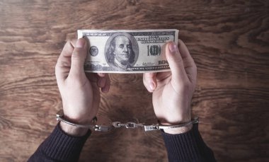 Elleri kelepçeli, ellerinde dolar banknotları var. Yozlaşma