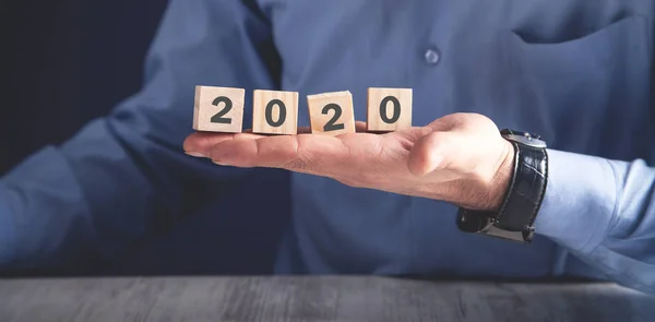 Muž držící dřevěné kostky s 2020 rokem. — Stock fotografie