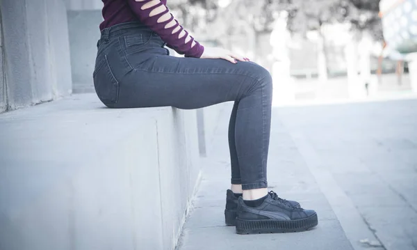 Mode modell i svarta jeans sitter i utomhus. — Stockfoto