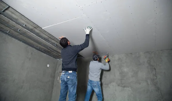 Werknemers montage paneel in het frame van het plafond. — Stockfoto