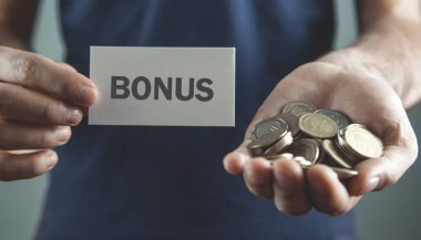 Elinde kartvizit ve bonus metni olan bozuk para tutan adam..