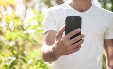 Beyaz adam doğada akıllı telefon kullanıyor..