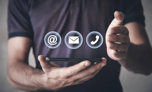 Man holding smartphone with contact symbols.