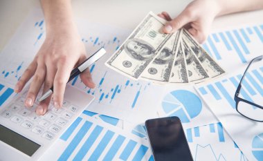 İş kadını hesap makinesi kullanıyor ve dolar tutuyor.. 