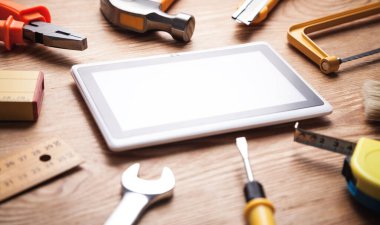  Ahşap arkaplan üzerine tablet kullanan çalışma araçları.