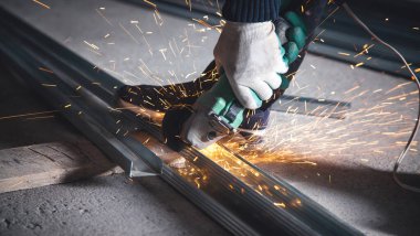 Adam metal profilini öğütücüyle kesiyor. Endüstriyel kavram