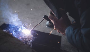 Kaynakçı koruyucu maskeli metaller üzerinde kaynak yapıyor.. 