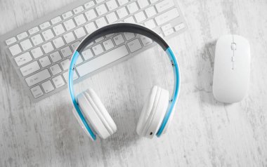 Bilgisayar klavyesi ve faresi olan beyaz kulaklıklar. İş masası