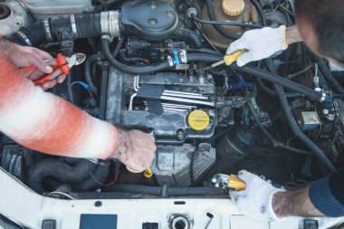 Otomobil tamirinde çalışan insanlar. Aletlerin elleri