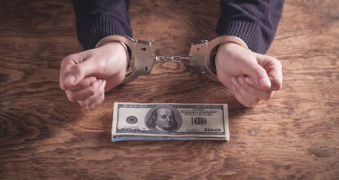 Elleri kelepçeli, ellerinde dolar banknotları var. Yozlaşma