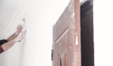 İşçi duvarı zımpara kağıdıyla öğütüyor. Yenileme