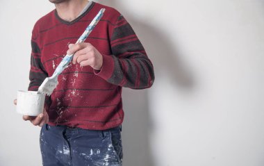 Adam fırçayı beyaz boyayla boyuyor. Yenileme