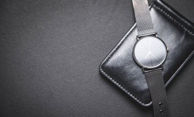 Siyah arka planda kol saati ve cüzdan..